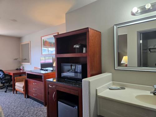 a bathroom with a sink and a desk with a mirror at Olympia Inn in Colorado Springs