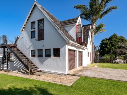 a white house with a staircase and a palm tree at Be at Rest Accommodation in George