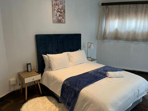 a bed with a blue headboard in a bedroom at Forest Crescent Villa - Pecanwood Golf Estate, Hartbeespoort in Hartbeespoort