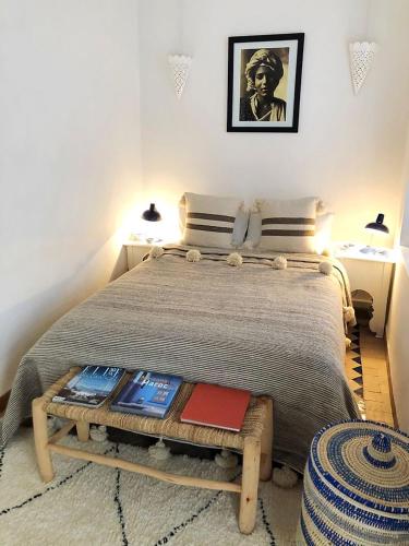a bedroom with a bed with a table with books on it at Art riad au bord de la mer 2 in El Jadida