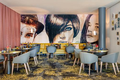 a restaurant with tables and chairs and a large mural at Novotel München City in Munich