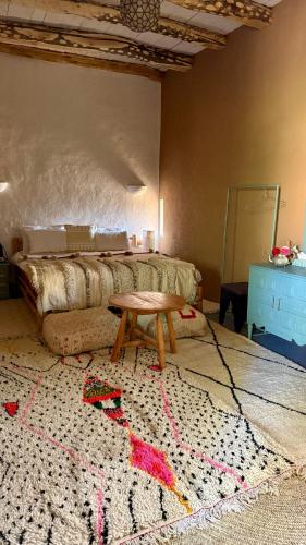 a bedroom with a bed and a table on a rug at Agafay Desert Hotel in El Karia