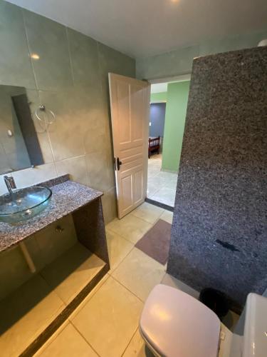a bathroom with a sink and a toilet and a door at Espaço dos Lobato in Miguel Pereira