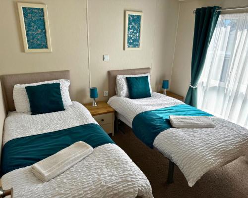 two twin beds in a room with a window at Meadows 90 - Southview Holiday Park Skegness in Skegness