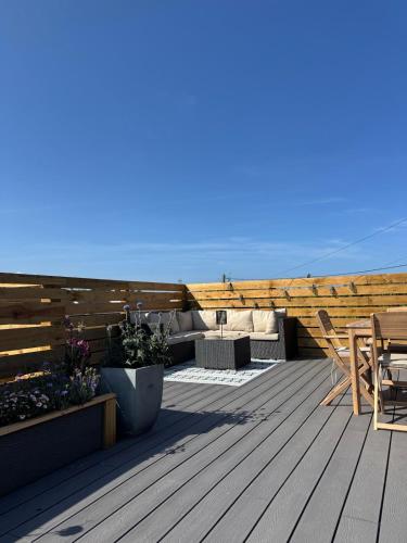a patio with a wooden deck with a table and chairs at The Beach Hut in Perranporth
