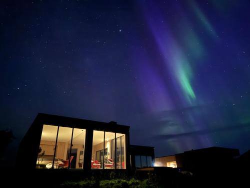 a glass house with the northern lights in the sky at NEW - Seafront Luxury Villa near Henningsvær in Kleppstad