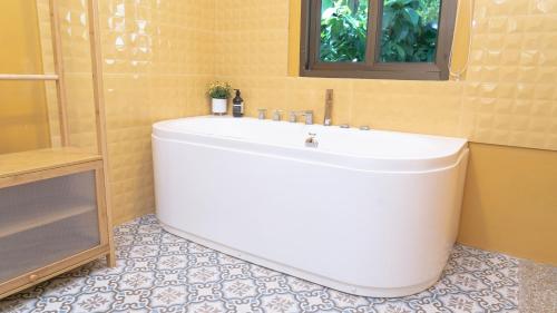 a large white tub in a bathroom with a window at Jaokhun Hilltop Patong, Phuket in Patong Beach