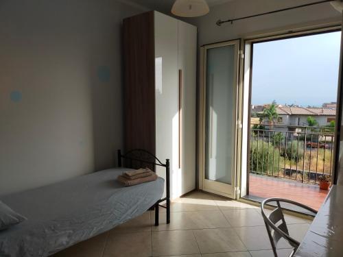 a bedroom with a bed and a sliding glass door at Etna House in Santa Maria di Licodia