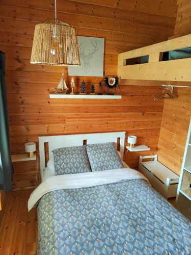 a bedroom with a bed in a wooden room at Le cottage des rives de l'Aa labélisé 3 étoiles in Bourbourg