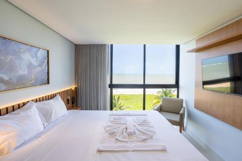 a bedroom with a large white bed and a chair at Alta Garden Housi João Pessoa by Carpediem in João Pessoa