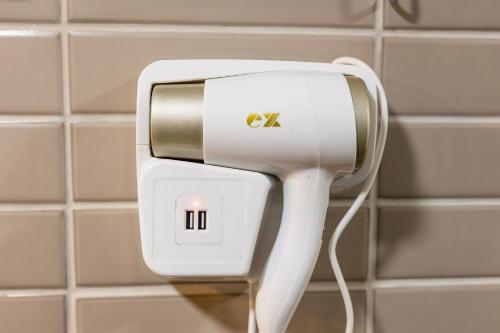 a white hair dryer on a wall in a bathroom at Alta Garden Housi João Pessoa by Carpediem in João Pessoa