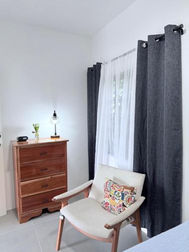 a bedroom with a chair and a dresser and a window at Madgita Palm Villa in Port Antonio
