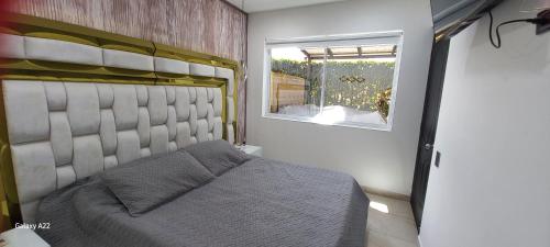a small bedroom with a bed and a window at Hotel y Cabañas Parinzzi in Guatapé