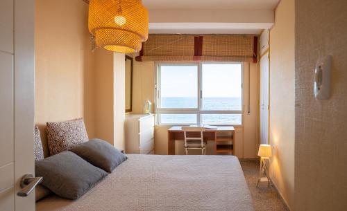 a bedroom with a bed and a desk and a window at Frente al mar y a pie de playa in Torrenueva