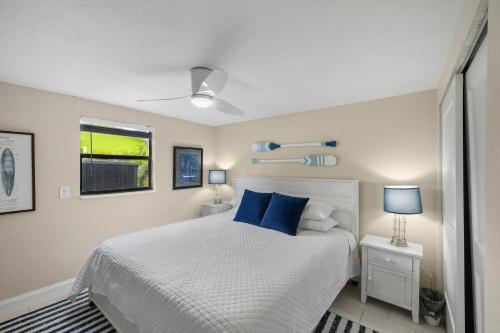 a bedroom with a white bed with blue pillows at Waterfront oasis with NEW POOL and kayaks in Hernando Beach