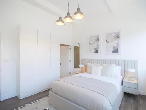 a white bedroom with a white bed and two lamps at Large City Centre Apartment Stylish and Spacious in Manchester