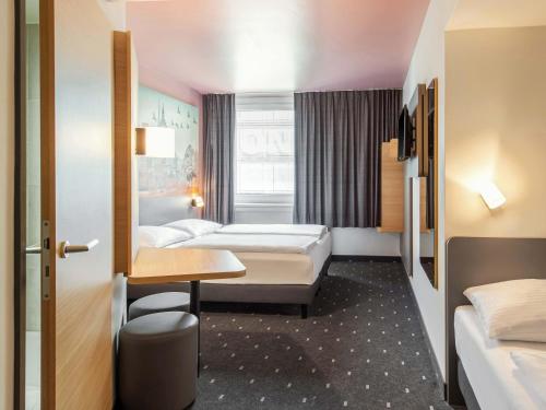 a hotel room with two beds and a table at B&B Hotel Nürnberg-Hbf in Nürnberg