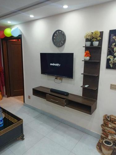 a wall with a tv and a clock on a wall at One bed apartment in Lahore in Lahore