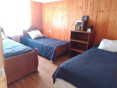 two beds in a room with wooden walls and wooden floors at Cabaña Puipuyen Yerbas Buenas 