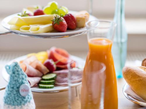 a plate of food with fruit and a plate of orange juice at Strandhaus Ahrenshoop in Ahrenshoop