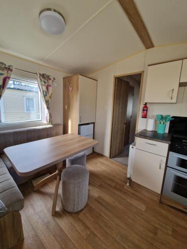 a kitchen and living room with a wooden table at J & C caravans in Saint Osyth