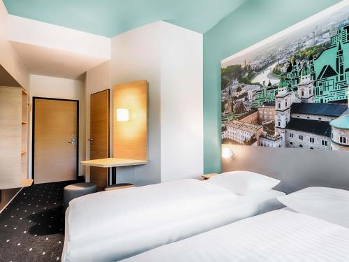 two beds in a room with a painting on the wall at B&B Hotel Salzburg-Nord in Salzburg