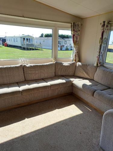 a couch in a living room with a large window at J & C caravans in Saint Osyth