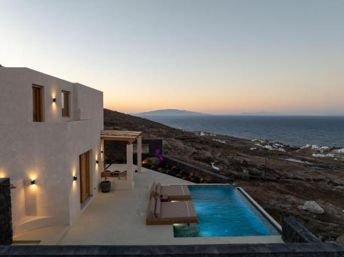 a villa with a swimming pool next to the ocean at Athera Luxury Villas in Santorini