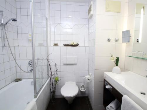 a white toilet sitting next to a bath tub at AMBER ECONTEL in Munich