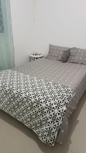 a bed with a black and white comforter on it at la casita de Daniela in San Miguel