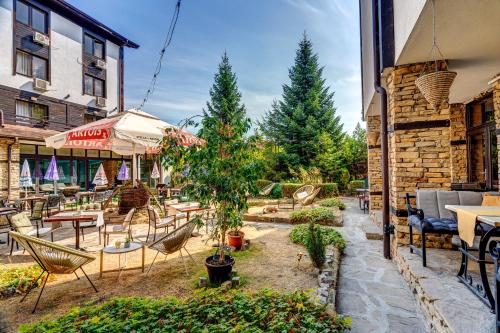 a patio with tables and chairs and a tree at Hotel Bansko SPA & Holidays - Free Parking in Bansko