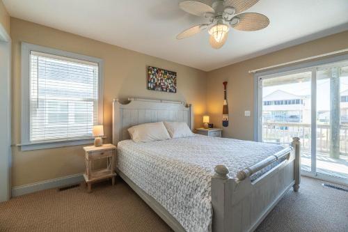 a bedroom with a bed with a ceiling fan and windows at K1618 Lollygaggers - 3 Night Min Yr Rnd! Elevator, Pool, Cabana, Rec Room, Pets OK! in Croatan Shores