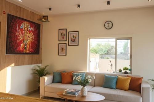 a living room with a couch and a clock on the wall at Hotel Radhika in Somnath