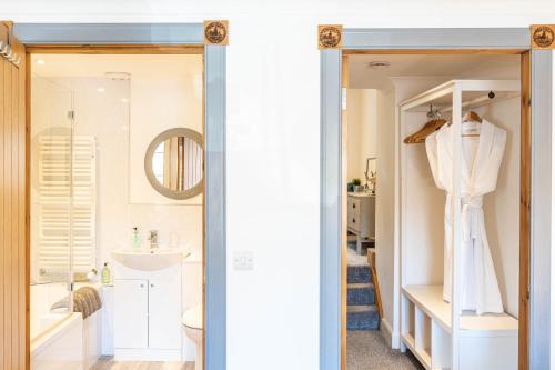 a bathroom with a sink and a white robe on a rack at The Merchants House in Pittenweem
