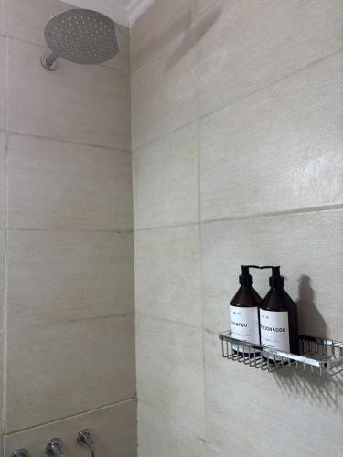 a bathroom with a shower with three bottles of soap at Calle Italia in Rosario