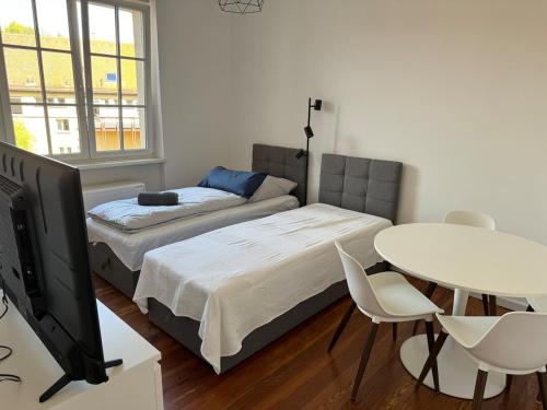 a room with two beds and a table and a tv at Apt4 - Ferienwohnung Brötzingen 3 OG in Pforzheim