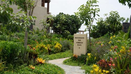 a sign in the middle of a garden with flowers at Minimalist elegance by the beach in Zihuatanejo