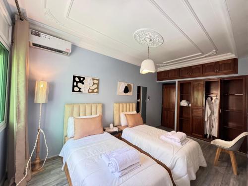 a bedroom with two beds and a table with a chair at Rami Home in Casablanca