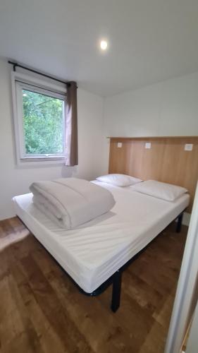 a large white bed in a room with a window at Camping du Riuferrer in Arles-sur-Tech