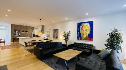 a living room with a black couch and a kitchen at OlofPalmesApartment Premium in Stockholm