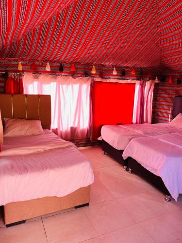 two beds in a room with red curtains at Bedouin Spirit Camp & Tours in Wadi Rum