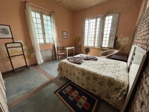 a bedroom with a bed in a room with windows at Pousada Charqueada Costa do Abolengo in Pelotas