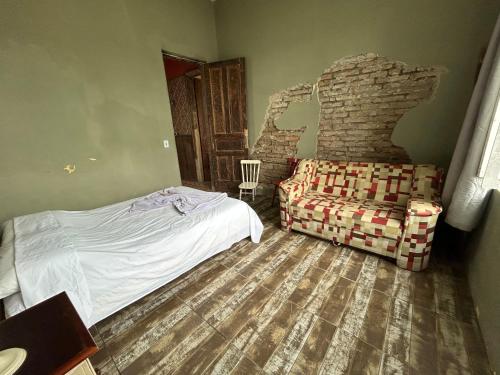 a bedroom with a bed and a couch and a chair at Pousada Charqueada Costa do Abolengo in Pelotas