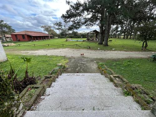 a path in a field with a house in the background at Pousada Charqueada Costa do Abolengo in Pelotas
