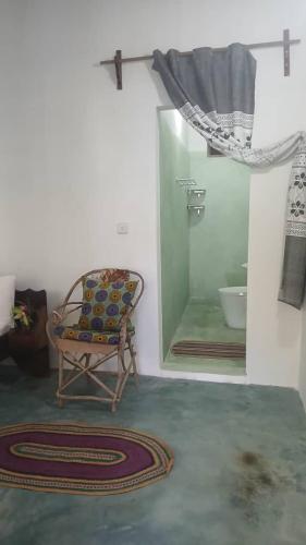 a room with a chair and a shower with a mirror at Beach Front Bungalow in Jambiani