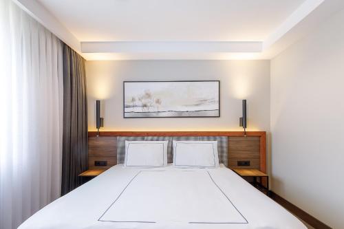 une chambre avec un grand lit blanc avec deux oreillers dans l'établissement Regnum Bansko Ski Hotel & SPA, à Bansko