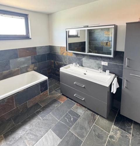 a bathroom with a tub and a sink and a bath tubermottermott at das Haus in Jois in Jois