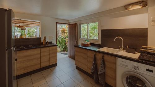 a kitchen with a sink and a washing machine at Beach apartment, Ti Clé de Lo in Pointe-Noire