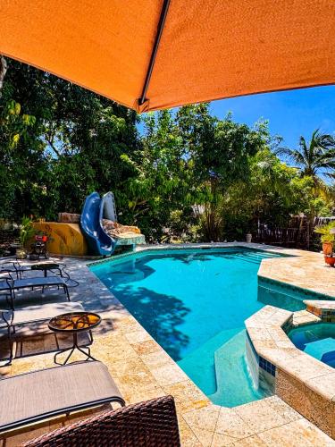 a swimming pool with an orange umbrella and a playground at Caribbean Shores Belize in Hopkins