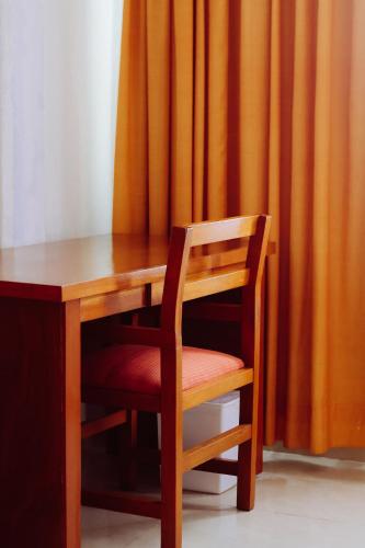 a wooden desk with a chair next to a curtain at Hotel Báez Carrizal in Villahermosa
